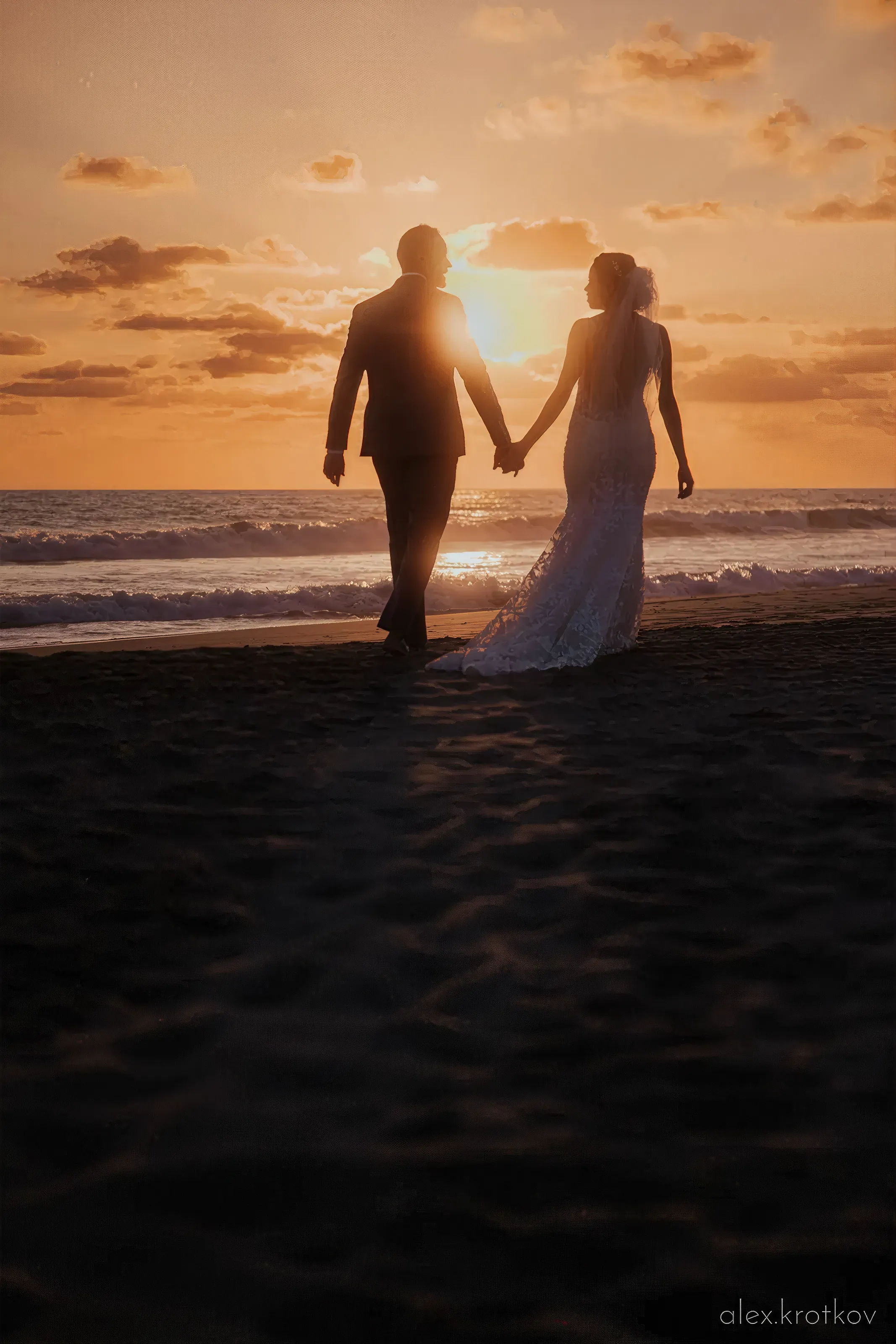 Married couple hold hands facing a sunset